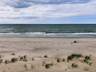 Lonely human silhouette at the wild empty beach, sea view background
