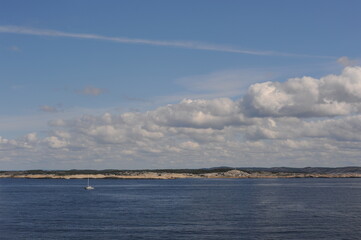 White clouds in the blue sky in Skagerrak Strait near Str&ouml;mstad between Sweden and Norway on a sunny day with navy blue sea in summer