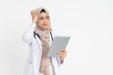 veiled female doctor wearing white suit uniform confused while looking at pad screen with hand scratching head
