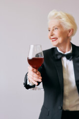 stylish senior sommelier woman in tuxedo with glass or red wine. Beverage, mature, style concept