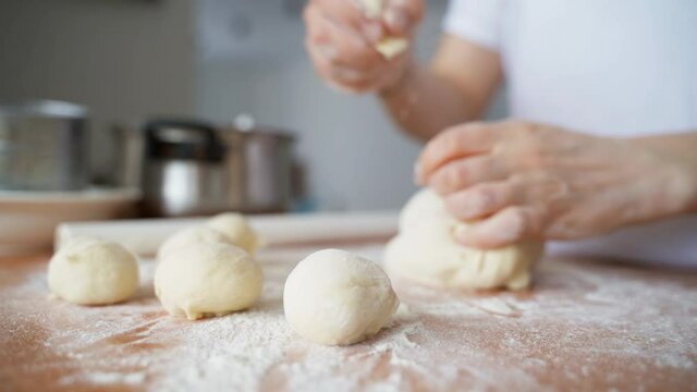 The woman divides the dough into equal pieces. Cooking pies. Hands close up. Female hands in the kitchen sculpt dough for baking.