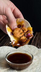 Hand spreading homemade taco with chicken, cheese and onion in bbq sauce with low key composition