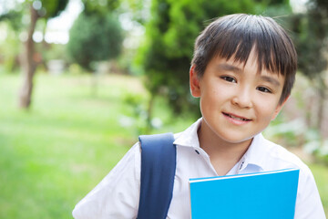 Happy cute asian schoolboy boy with books outdoors. Back to school