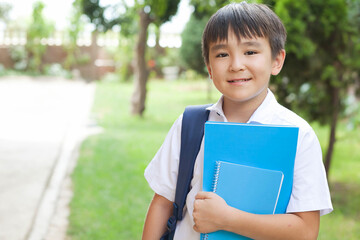Happy cute asian schoolboy boy with books outdoors. Back to school