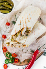 Shawarma with chicken, with sauce, onions, pickles, herbs and hot red pepper on a light background