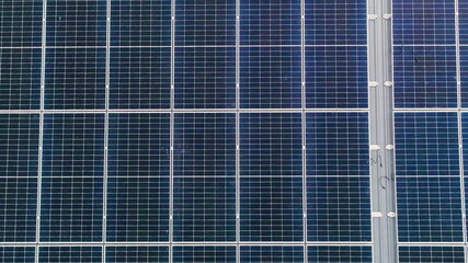 Fototapeta premium Photovoltaic solar panels on roof get clean energy from the sun. Slow motion. Aerial view. Solar Panel Array. Drone Aerial View of Modern Photovoltaic Electricity System, Close Up