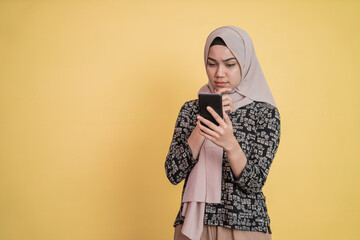 veiled woman looking at screen while using a smartphone with worried expression with copyspace