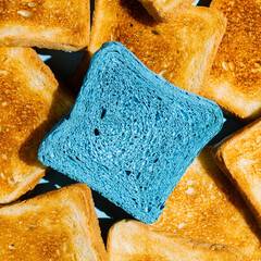 Pile of fried toast bread loaves and a loaf painted in blue. Close up texture of bread. Morning...