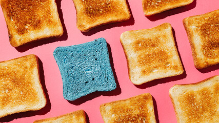 Close up pattern of French toast loaves with one blue toast on a bright pink background. Bread...