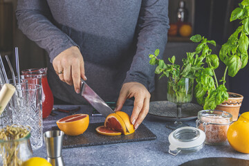 Woman hands cut grapefruit of knife on cutting board