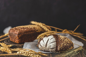 Gluten free food. Two healthy loaves of bread with grain and ears on dark table. Gluten free rye bread