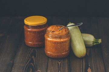 Squash zucchini paste or caviar in a glass jar surrounded by the ingredients on dark wooden table