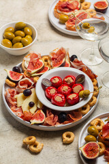 Traditional italian aperitivo, snacks and vermouth cocktail. Bruschetta, cold cuts of prosciutto, cheese, tuna fish stuffed mini bell peppers, taralli, olives, grapes and figs. Vertical image. - obrazy, fototapety, plakaty