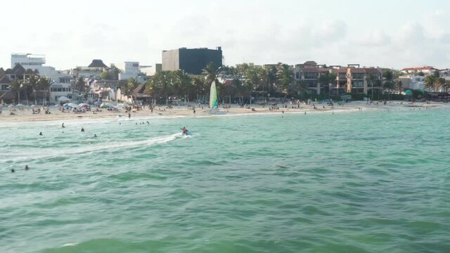 Stunning beachscape with sandy beach and holiday resorts. People swimming in turquoise sea water