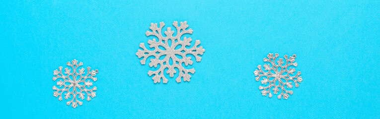 Beautiful Christmas border with silver snowflakes on blue paper background. Top view, flat lay.