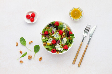Salad with lettuce roquefort cheese raspberries walnuts and vinaigrette on white background