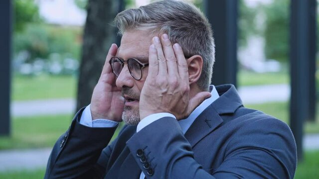 Middle-aged man suffering headache and panic attack, breathing fresh air outdoor