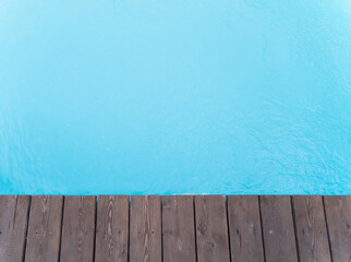 The edge of the swimming pool. Wooden floor at the entrance to the water