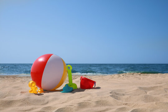 Many different sand toys and beach ball near sea, space for text