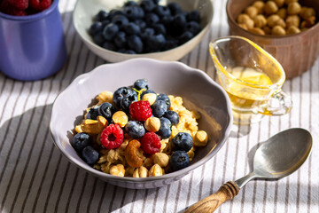 Oatmeal with berries and honey for breakfast.Oatmeal with coconut milk and berries.Healthy and trendy breakfast. Schoolchild's breakfast.Delicious porridge with berries and syrup for proper nutrition.