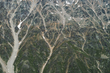 The texture of the mountain. The relief of a mountain slope with snow. Abstract natural background.