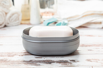 soap on a gray plastic soap dish, on a white wooden table.