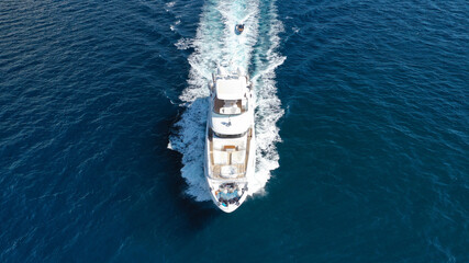 Aerial drone photo of luxury yacht cruising in deep blue sea near island of Mykonos, Cyclades, Greece