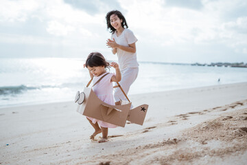 kid running at the beach play with cardboard toy airplane