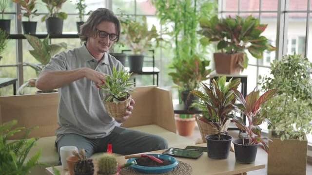 Man taking care of her potted plants at home