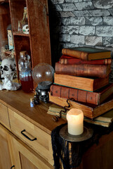 The House of Magic, Halloween decoration with spooky objects. Still life with old books, crystal ball and candle.