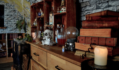 Witch house, Halloween decoration with spooky objects. House of magic. Still life with old books, crystal ball and candle.