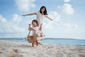 lovely mother and daughter playing with airplane cardboard toy