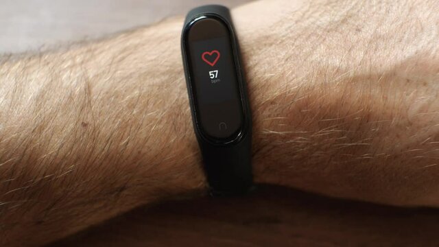 Close-up of the heart rate measurement on the fitness bracelet. The black device is worn on a man's wrist. The concept of monitoring one's health
