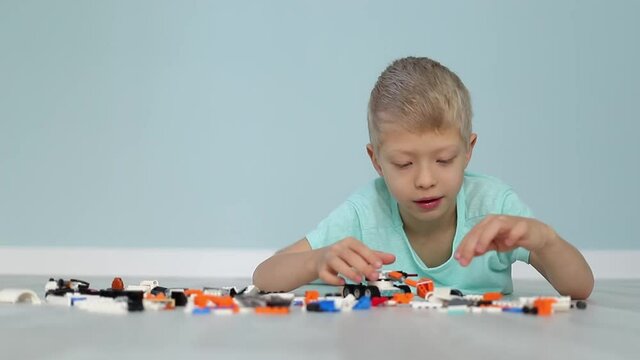 a child boy enthusiastically collects a constructor on the floor from small parts, development and leisure of preschool children
