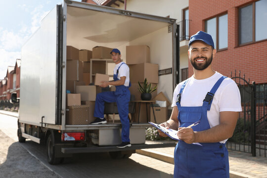 Moving service workers outdoors, unloading boxes and checking list