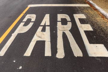 Asphalt track freshly made with some dirt and in the upper right corner the pollen of a tree. The word STOP is painted on the photo (in Portuguese)
