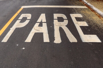 Asphalt track freshly made with some dirt and in the upper right corner the pollen of a tree. The word STOP is painted on the photo (in Portuguese)
