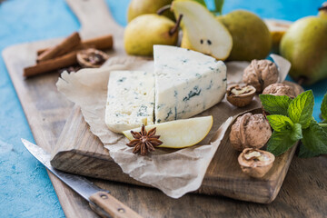 Fototapeta na wymiar Gorgonzola picant Italian blue cheese, made from unskimmed cow's milk in North of Italy. Piece of blue mould cheese danablu, roquefort with pear and walnuts