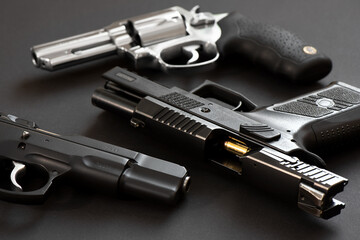 Two black pistols with Chrome revolver in the background.