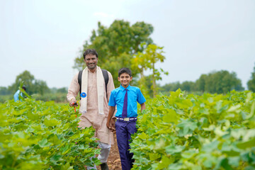 Fototapeta premium Young indian farmer with his son at green agriculture field.