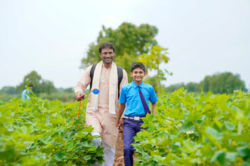 Fototapeta premium Young indian farmer with his son at green agriculture field.