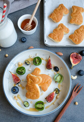 Healthy breakfast meal for the whole family. Healthy Breakfast. Animated shaped bread eaten with raw bee honey, milk, fresh figs, blueberries, kiwi berries, almonds, chickpeas and cashew nuts.