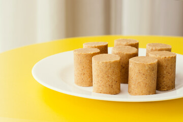 Peanut candy (called Paçoca) served on a plate and is on a yellow table. This sweet is traditional in Brazil.