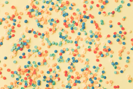 Colorful candies are neatly scattered on a yellow background