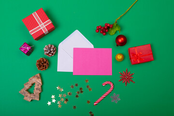 Composition of envelopes with christmas decorations and baubles on green background