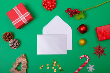 Composition of envelopes with christmas decorations and baubles on green background