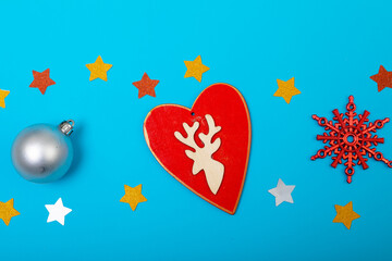 Composition of christmas decorations with silver bauble, heart and stars on blue background