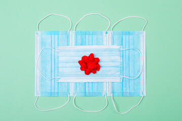 Composition of face masks with red ribbon on green background - Powered by Adobe