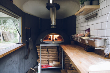 a mobile kitchen with a pizza oven burning inside