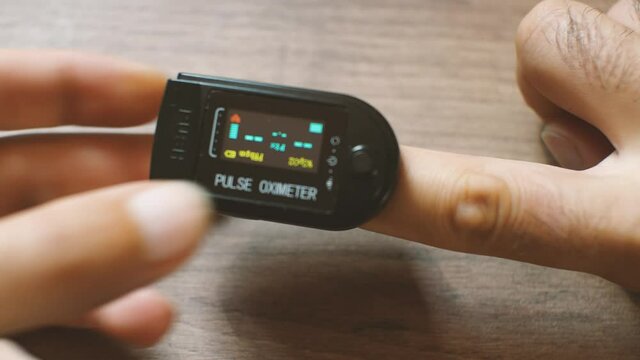 A man puts an Oxiometer on his finger. After a while, the measurement values are displayed on the LCD screen. Monitoring your own health